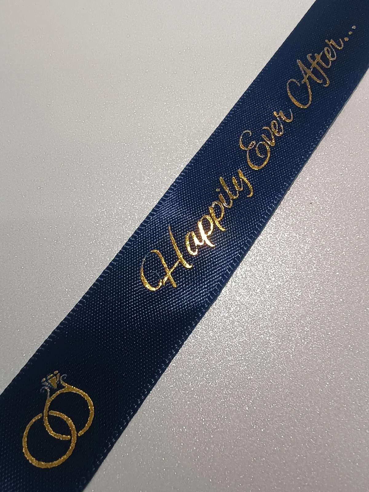 Navy ribbon with gold-coloured wedding lettering and linked-ring details