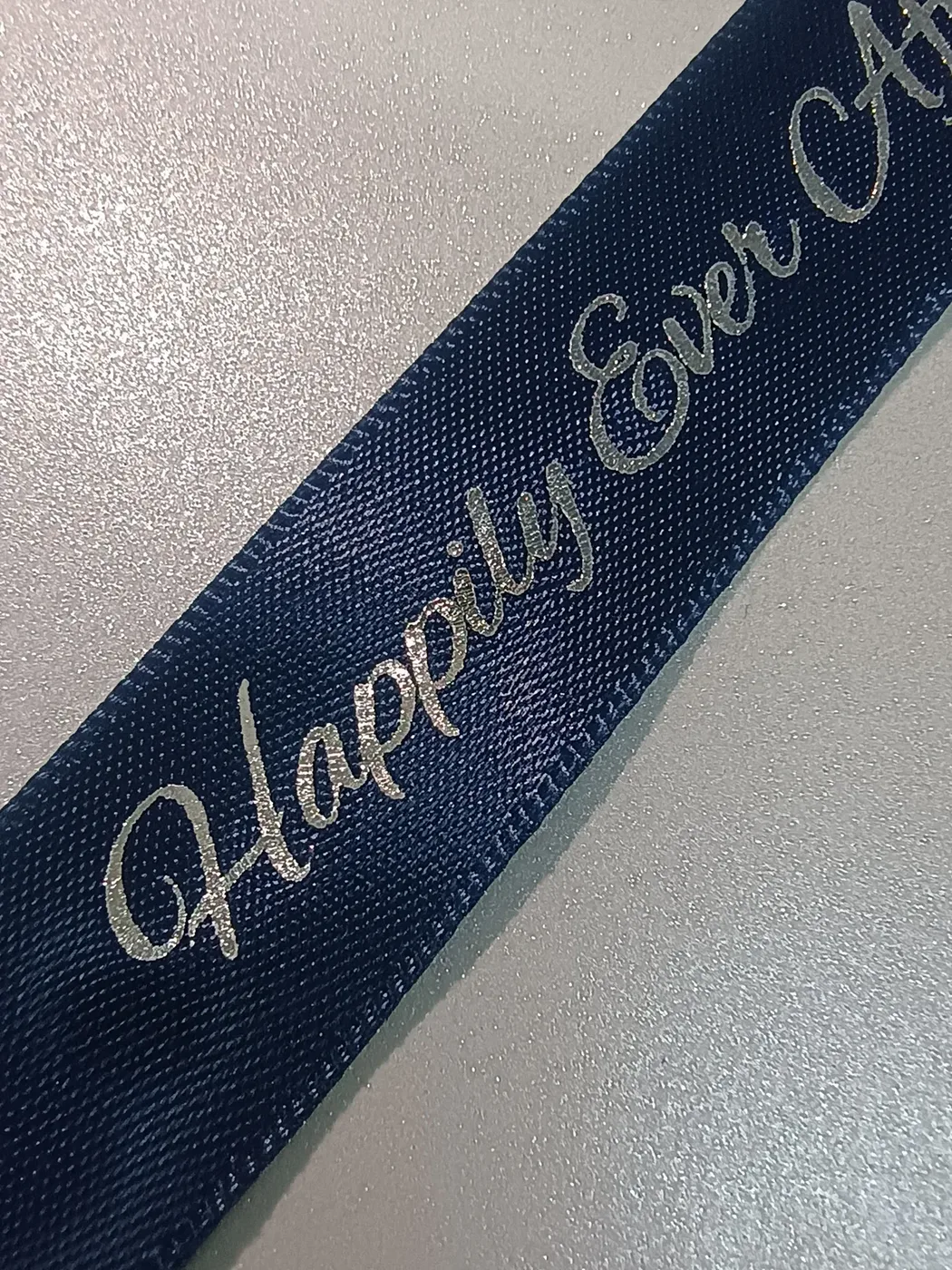A close view of silver-coloured wedding lettering on navy ribbon