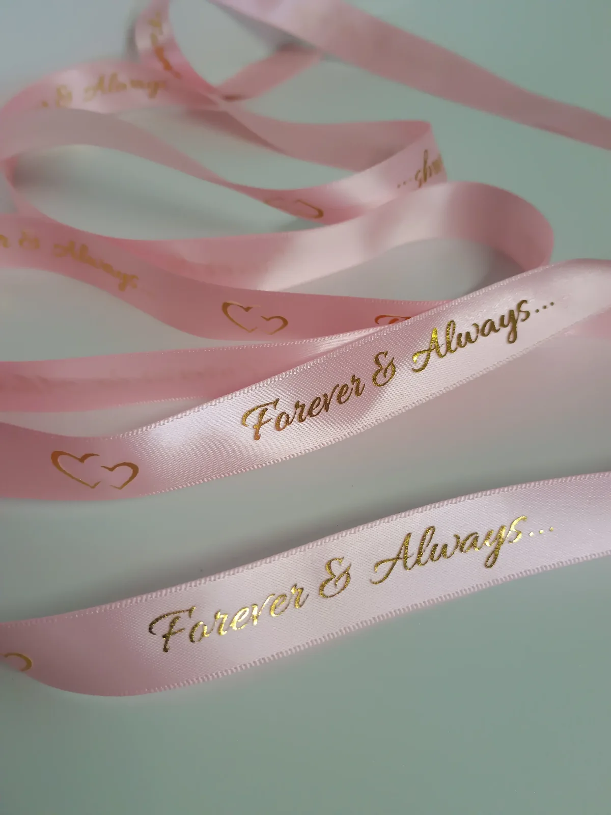 Pink ribbons with gold-coloured lettering and heart details